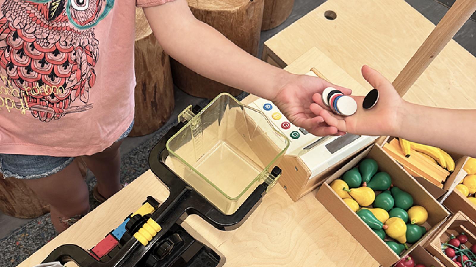 Hände von zwei Kindern tauschen Spielmünzen aus
